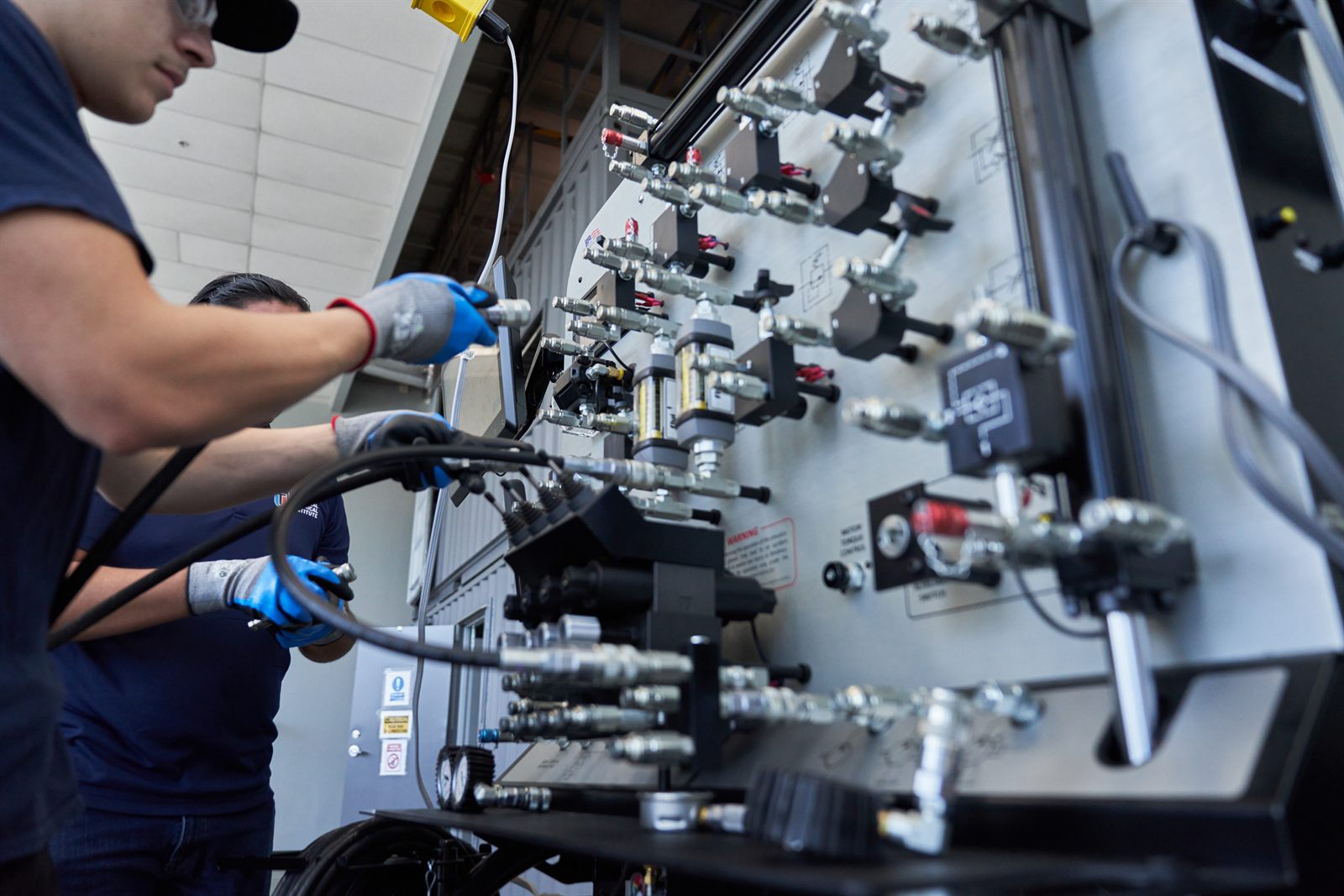 Technicians working on industrial hydraulic or pneumatic maintenance panel