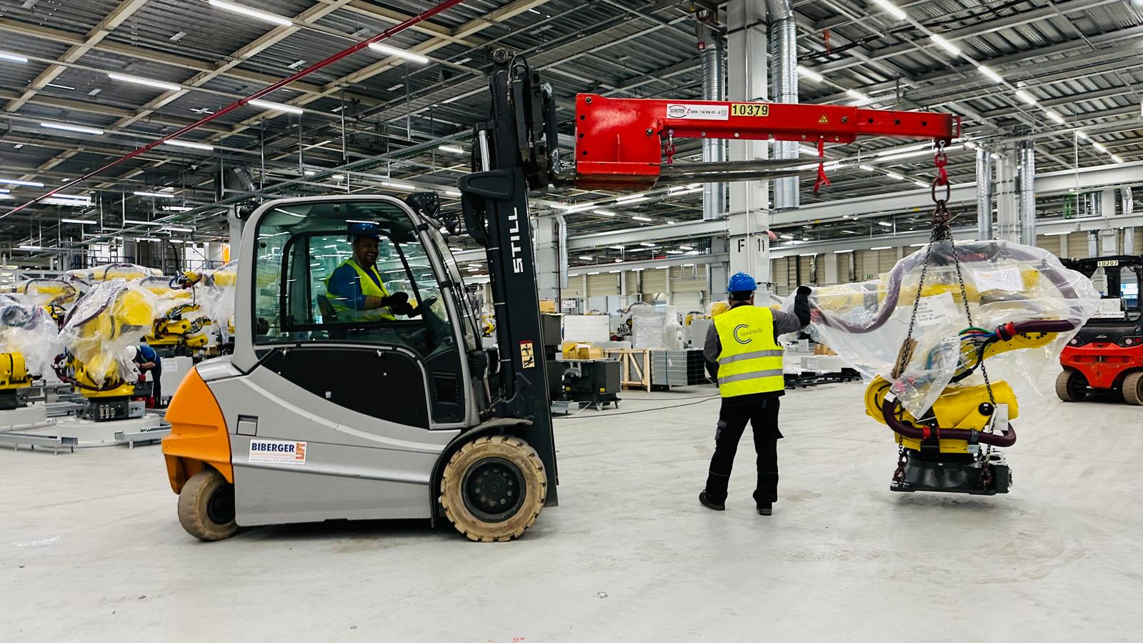 Forklift, worker and robot during industrial mechanical installation